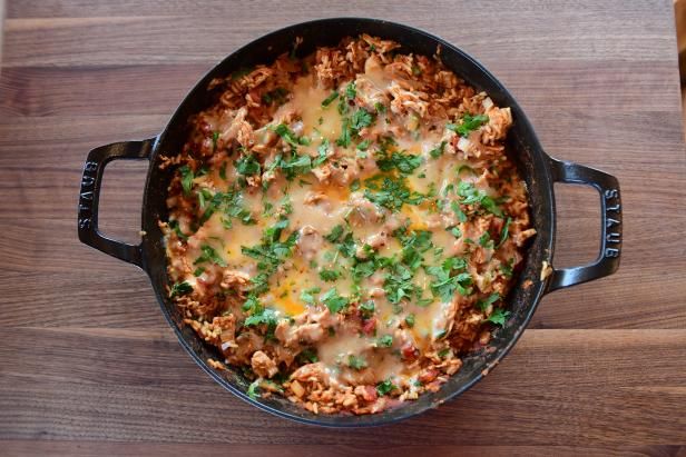 a casserole dish with meat, cheese and parsley in a black pan