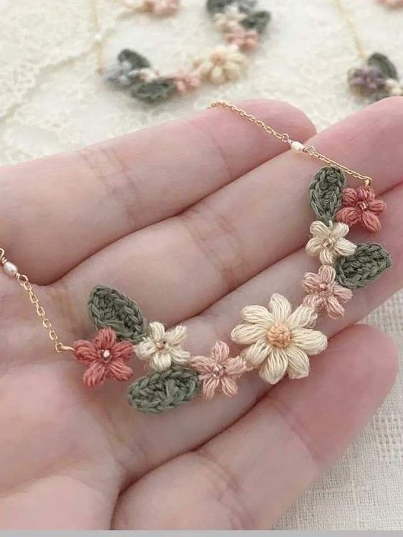 a hand holding a necklace with flowers on it