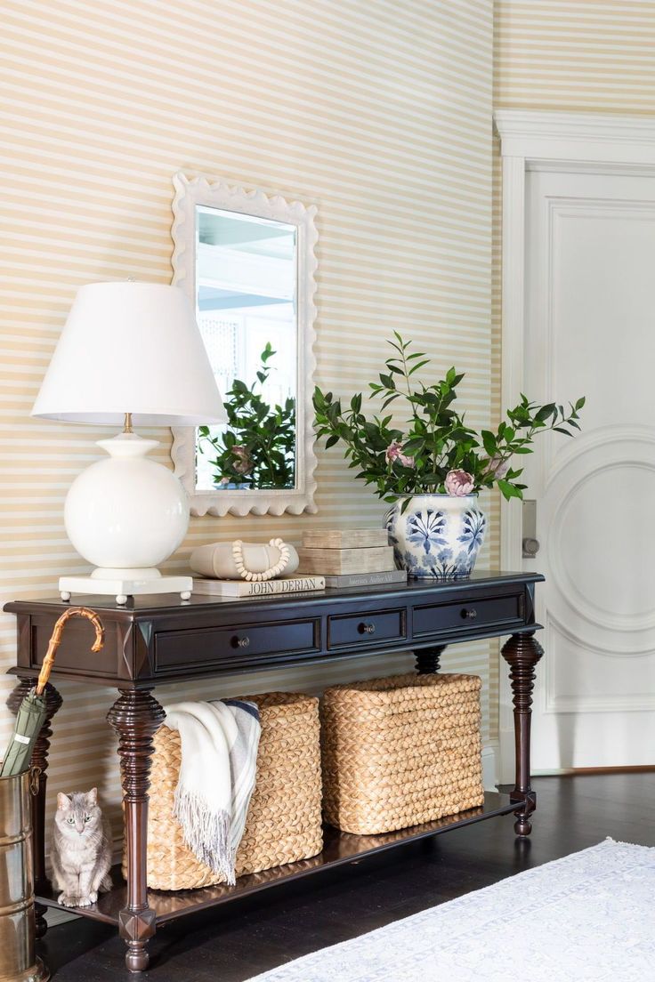 a console table with baskets on it and a lamp next to it in front of a white door