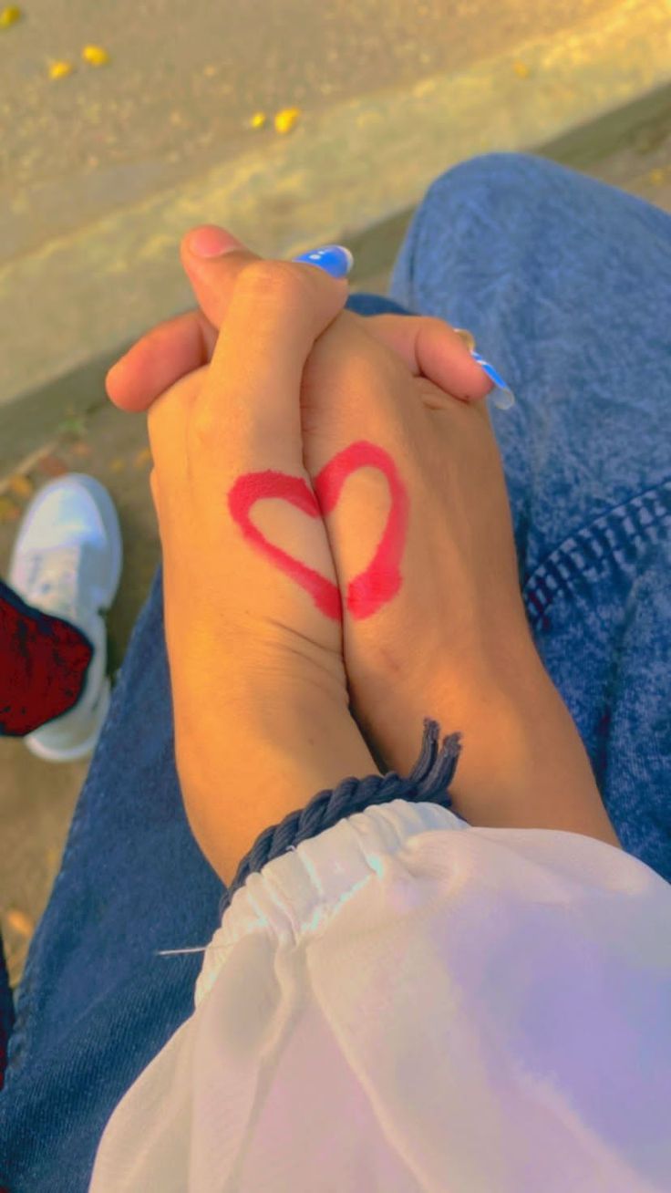 two people are holding hands with the word love painted on their wrists and one has a red heart