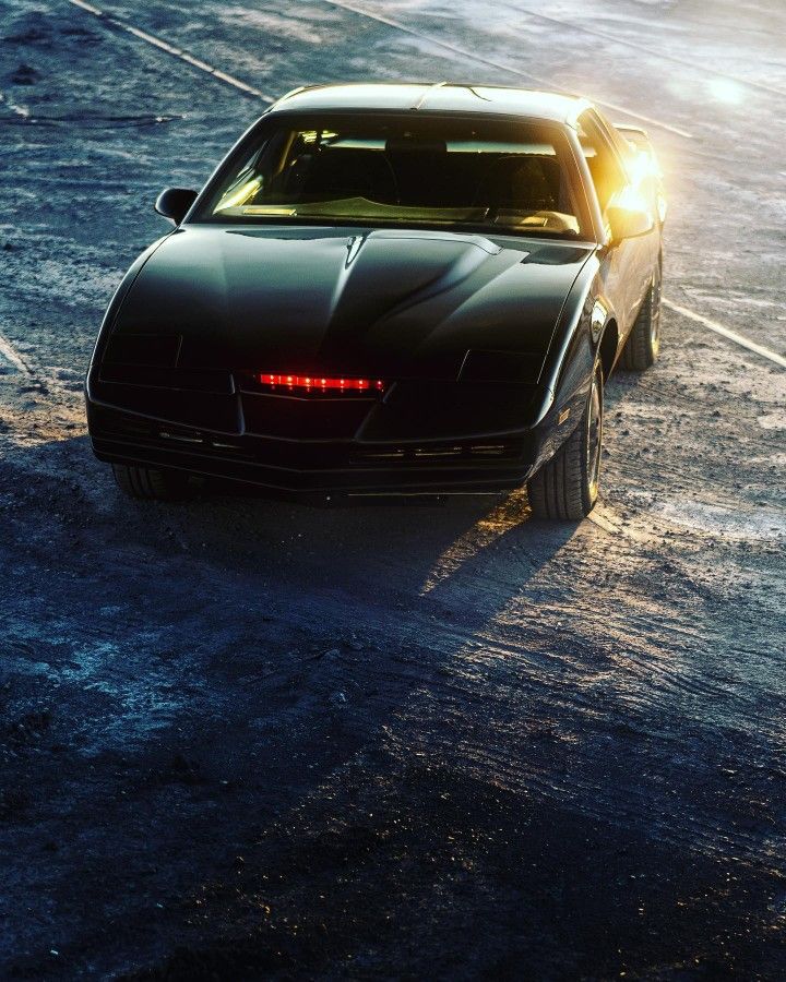 a black sports car driving down a wet road in the rain at sunset or dawn