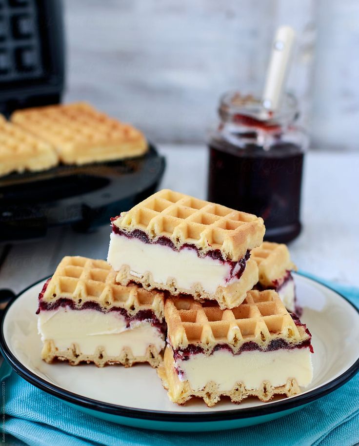 three waffles stacked on top of each other on a plate with syrup in the background