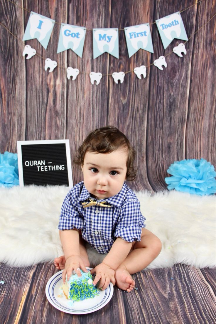 a baby is sitting on the floor in front of a backdrop