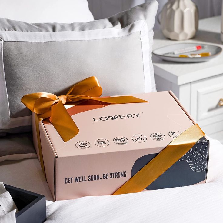 a box with a bow sitting on top of a bed next to pillows and pillow cases