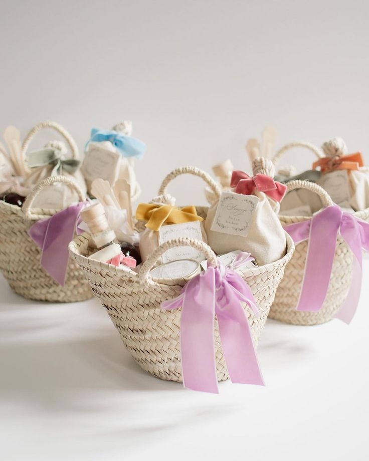 three baskets filled with baby items on top of a white table cloth covered floor next to each other