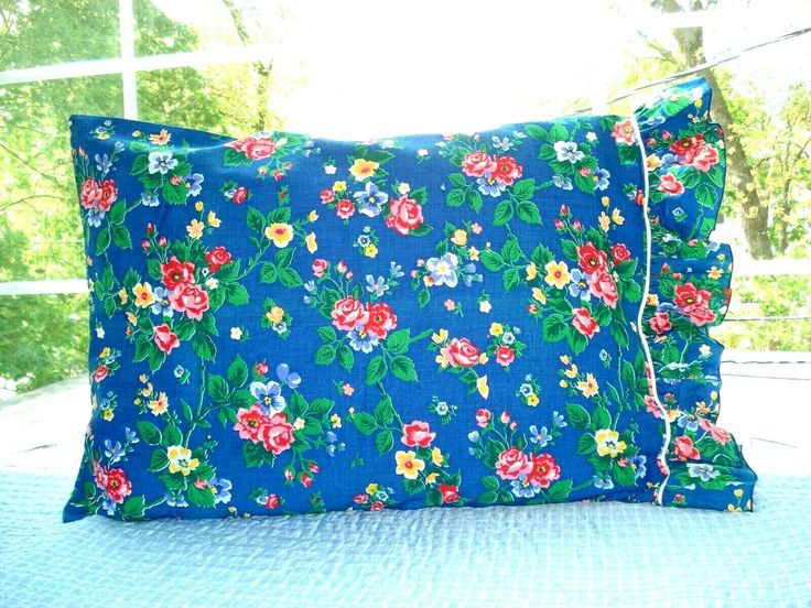 a blue pillow with flowers on it sitting on a bed