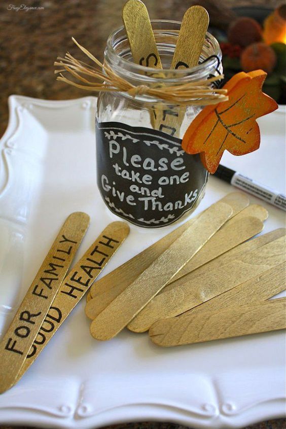 a glass jar filled with gold colored wooden spoons and some writing on the side