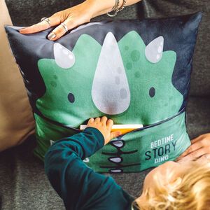 a child is drawing on a dinosaur pillow while someone holds the pillow up to their face