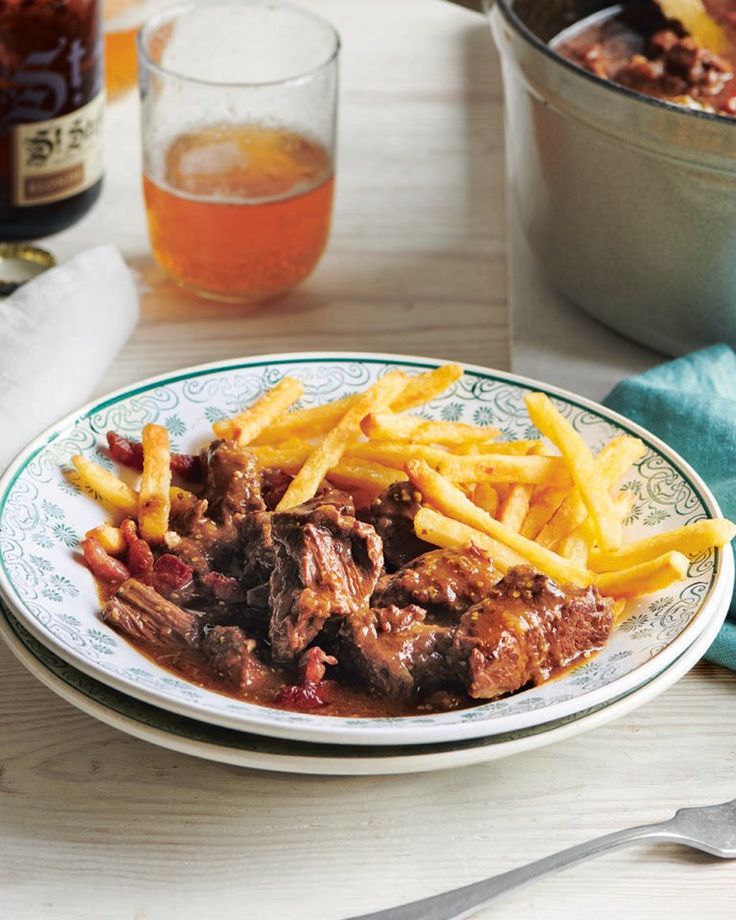 a white plate topped with french fries next to a pot full of chili and meat