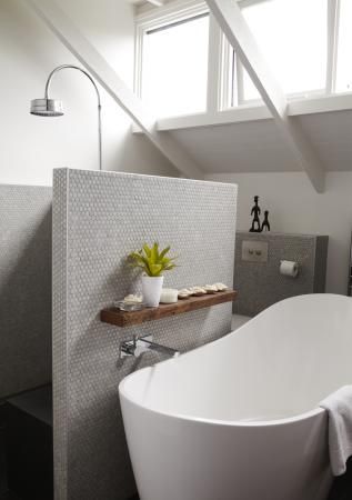 a white bath tub sitting under a window in a bathroom