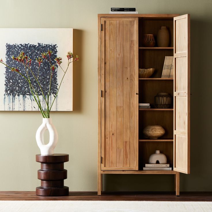 a wooden cabinet sitting next to a vase with flowers in it