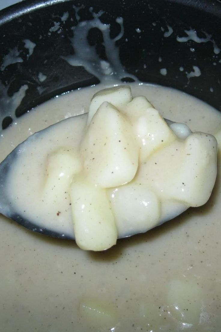 a spoon with some food in it on top of a pot filled with milk and cream