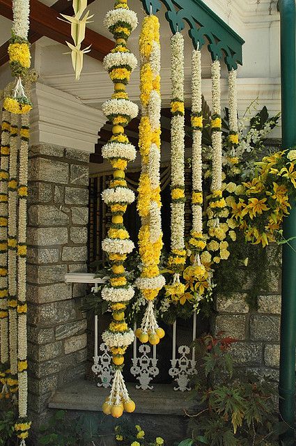 yellow and white flowers are hanging from the side of a building in front of a doorway