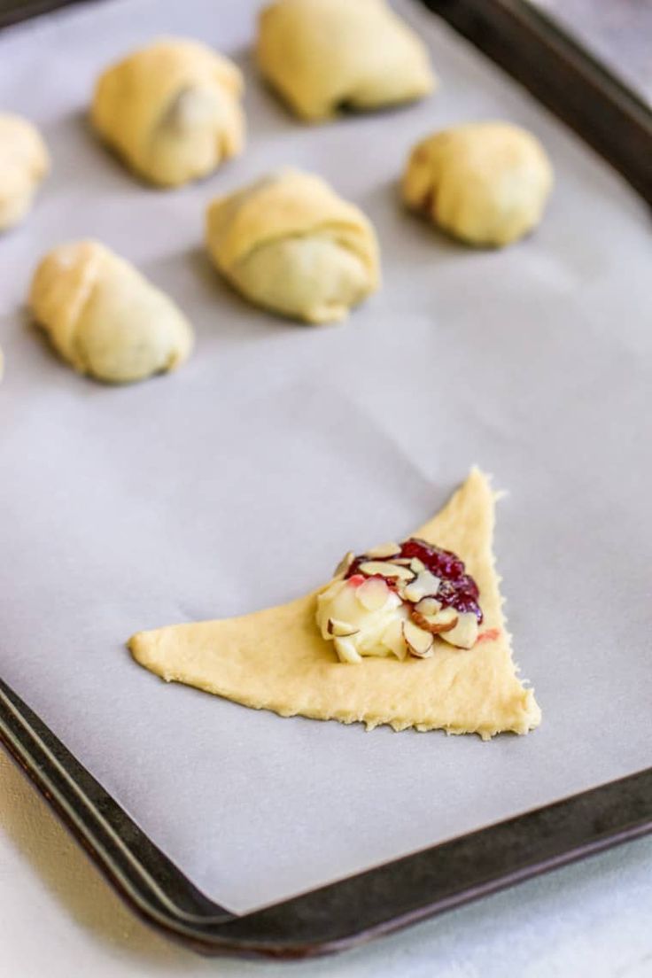 several pastries on a baking sheet with cranberry sauce in the middle,