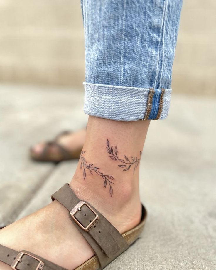 a woman's foot with a small flower tattoo on her left ankle and right leg