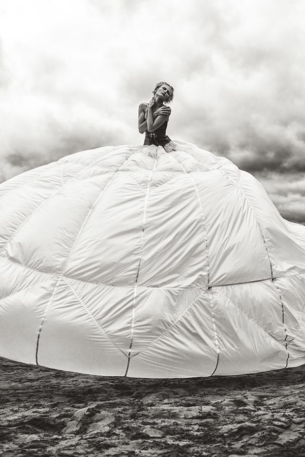 a woman sitting on top of a large white object in the ocean under a cloudy sky