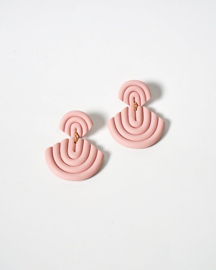 the pink earrings are made from plastic and have an intertwined design on each ear