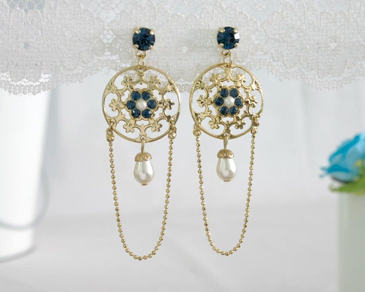 "This royalty-style gold and blue chandelier earring, which I've named Nancy, will softly touch you with a feeling of magic. Nancy is made from 24K gold plated brass and has delicate and feminine lacey filigree, set with blue crystals and Swarovski crystal pearls. A delicate Crystal Pearl teardrop swings romantically from the bottom of the pendant. Measurements: Earring length: 2.95\" (7.5cm) Pendant diameter: 0.7\" (2cm) About my work: All the jewelry in my shop is designed by me to evoke the r Bridal Chandelier Earrings, Black Gold Earrings, Chandelier Earrings Gold, Blue Bridal Earrings, Victorian Style Earrings, Blue Chandelier, Bridal Earrings Chandelier, Gold Chandelier Earrings, Crystal Bridal Earrings