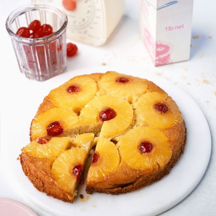 a pineapple upside down cake on a white plate next to a carton of yogurt