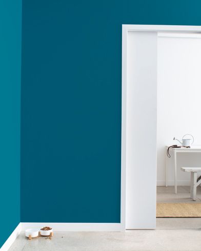 an open door leading to a bathroom with blue walls and white furniture on the floor