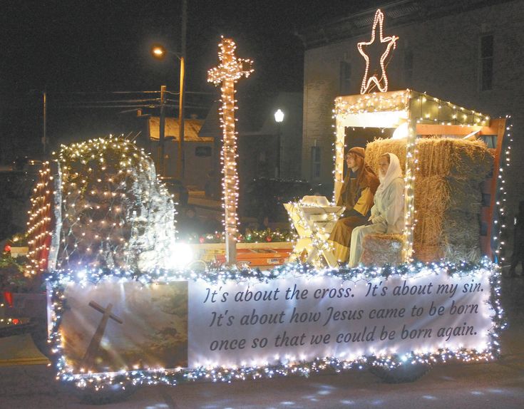 a float decorated with lights and decorations in the shape of a cross, on a city street at night