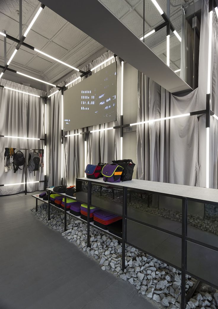 the interior of a sports store with many bags on display and lights above their windows