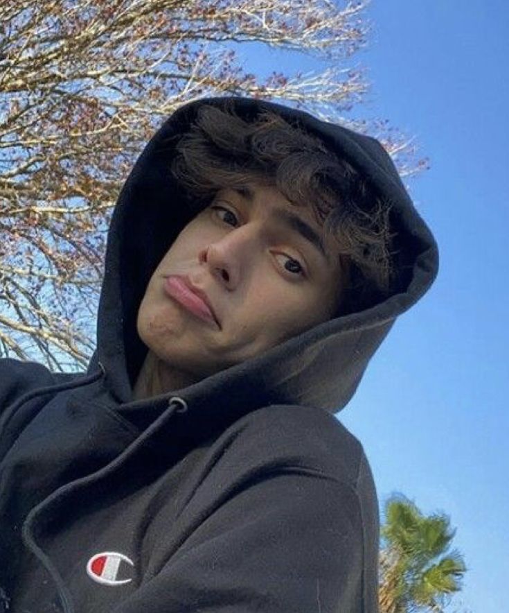 a young man in a black hoodie holding a cell phone