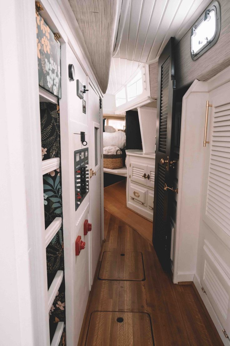 the inside of a tiny house with wood flooring and white cabinets on either side