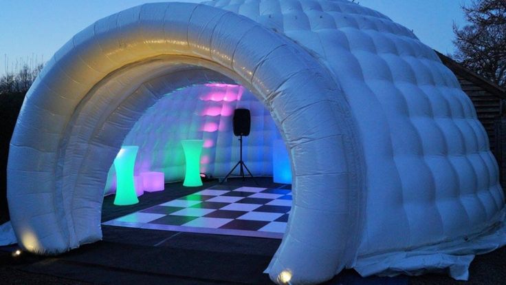 an inflatable tent is lit up with colored lights and checkered flooring