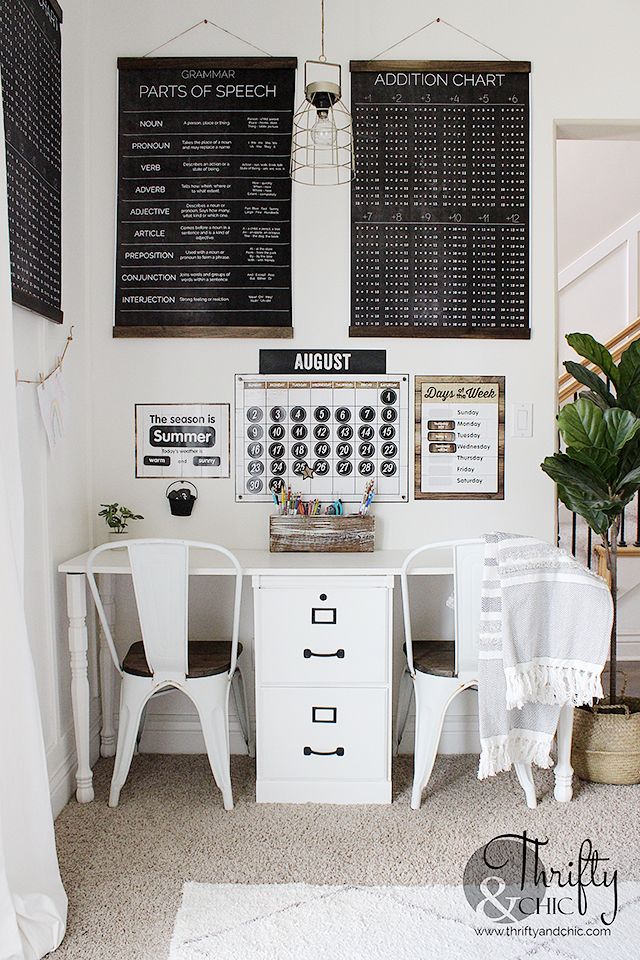 a white desk with two chairs in front of a wall mounted calendars on the wall