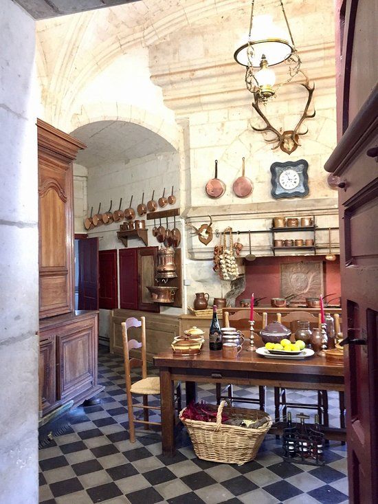 an old fashioned kitchen with black and white checkered flooring, wooden cabinets and hanging utensils