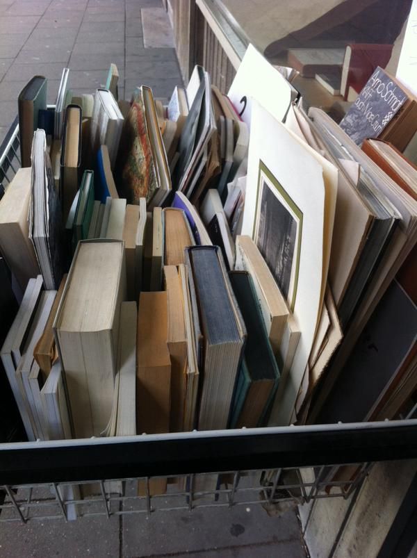 a pile of books sitting on top of a sidewalk