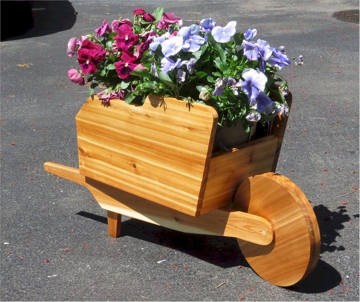 a wooden wagon with flowers in it sitting on the ground next to a parking lot