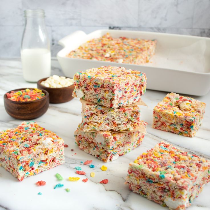 several pieces of cake with sprinkles next to a bowl of cereal and a glass of milk