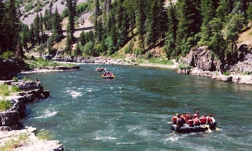 people are rafting down a river in the mountains