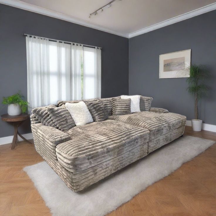 a large couch sitting on top of a wooden floor in a living room next to a window