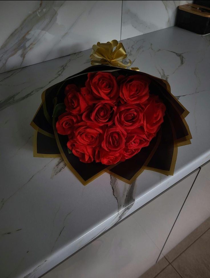 a bouquet of red roses sitting on top of a counter