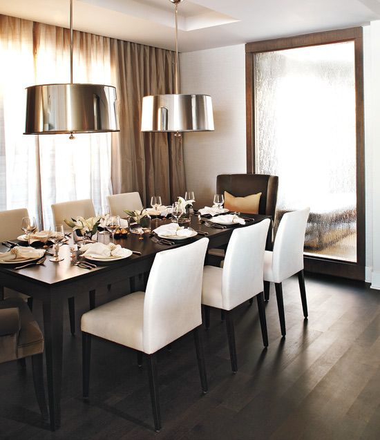 the dining room table is set for four with white chairs and place settings on it