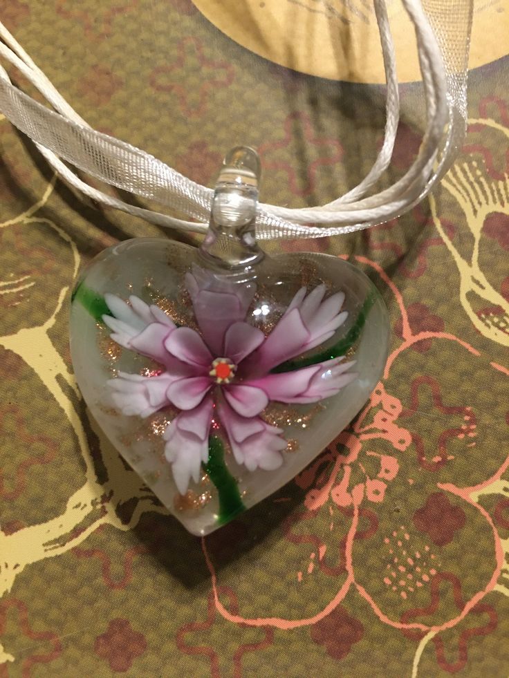 "Flower enclosed in glass necklace. Heart-shaped. Pretty pinks and lavenders. Heart is 1.5\" tall x 1\" across. Necklace is 8\" long closed." Artistic Pink Flower Jewelry, Pink Flower Glass Jewelry, Pink Flower-shaped Glass Jewelry, Clear Flower-shaped Necklace For Gift, Clear Flower Necklace For Gift, Clear Glass Flower Jewelry, Hand Painted Flower Necklace For Gift, Artistic Pink Necklace For Gift, Flower Shaped Glass Necklace For Gift