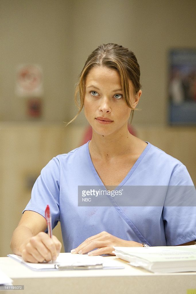 a woman in scrubs sitting at a desk with a pen and paper on it