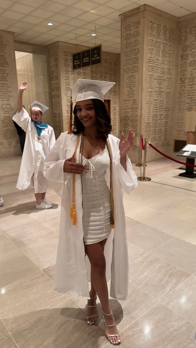 a woman in a graduation gown and cap is posing for the camera with her hands up