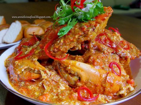 a white plate topped with meat covered in sauce and garnished with red peppers