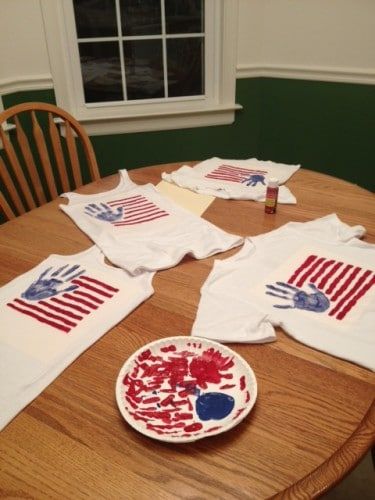 a wooden table topped with t - shirts covered in red, white and blue paint