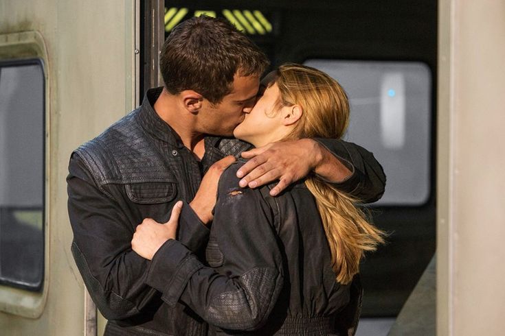 a man and woman embracing each other in front of a train door with their arms around each other