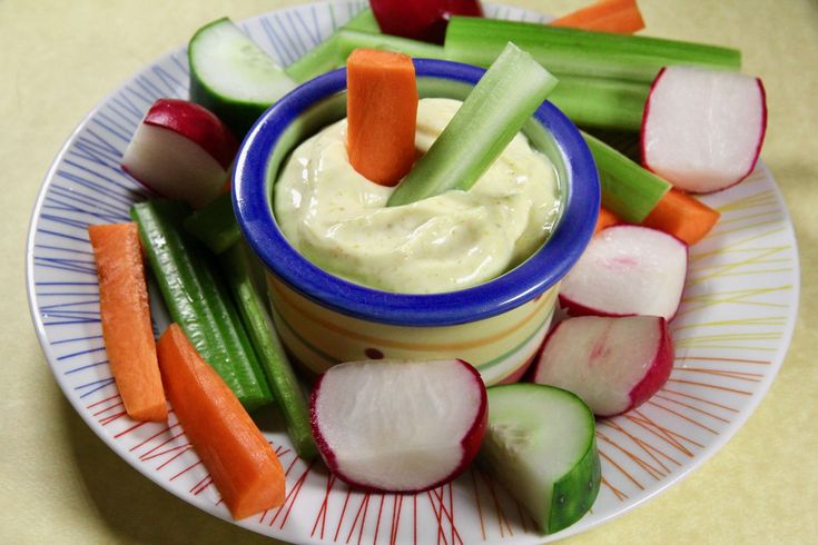 a plate topped with celery, carrots and cucumbers next to dip