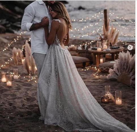 a man and woman standing next to each other in front of some lights on the beach