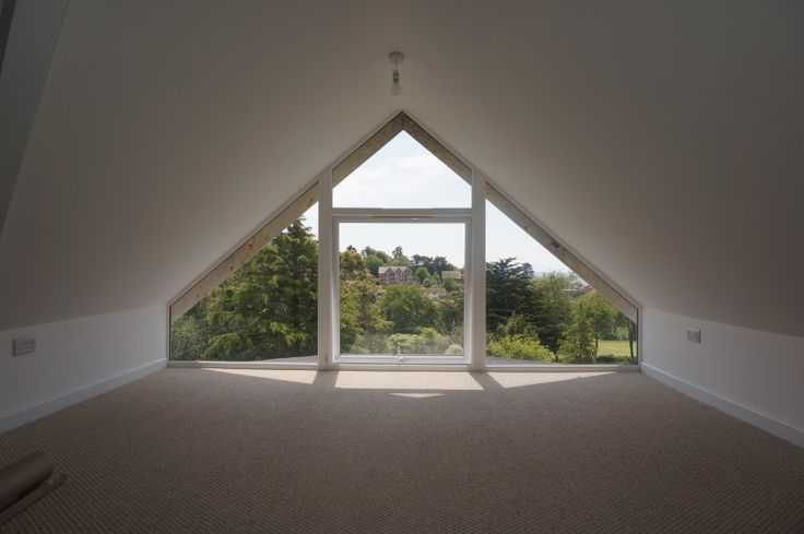 an empty room with large windows overlooking the trees