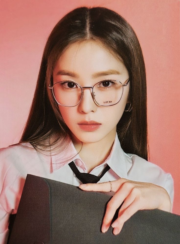 a woman wearing glasses and a tie is holding a book in front of her face