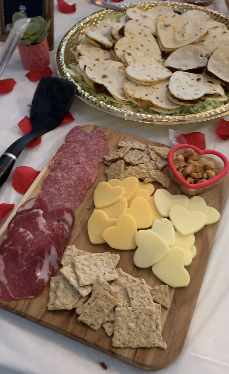 two platters of meat, cheese and crackers on a table