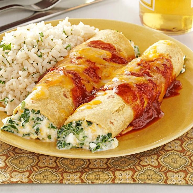 a yellow plate topped with two enchiladas and rice